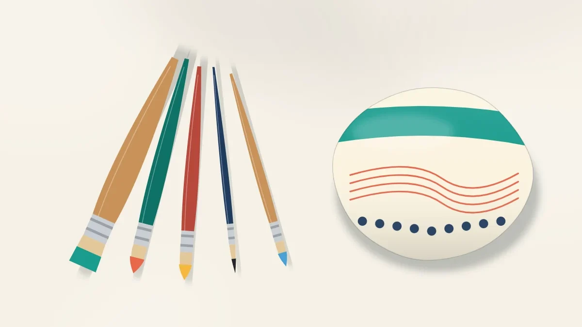 Five paintbrushes of different sizes fanned out next to a stone painted with broad color bands and fine line details