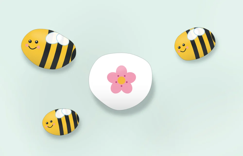 Three bumblebee stones of different sizes arranged around a stone painted with a pink flower