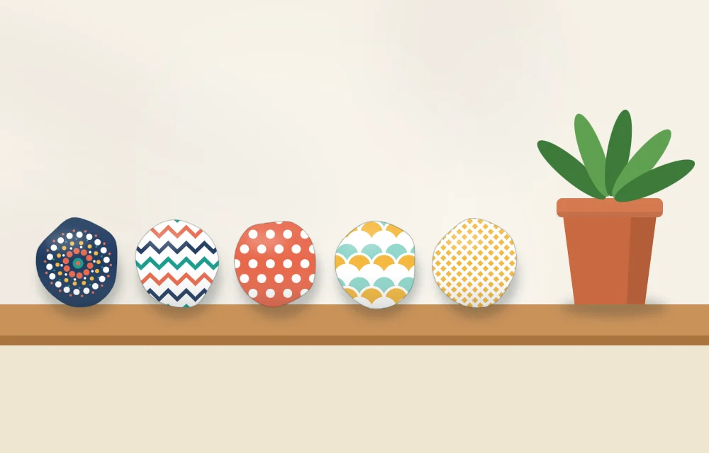Five patterned stones lined up on a shelf with a small potted plant at one end