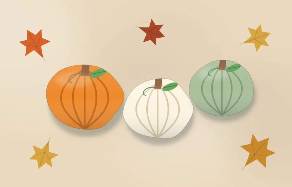 Pumpkin stones in orange, cream and sage green among scattered autumn leaves