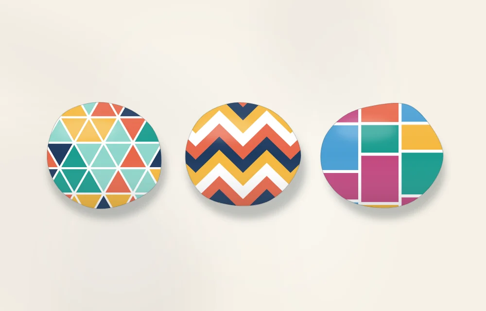 Three geometric stones side by side: a mosaic of triangles, bold chevrons and color blocks divided by white lines