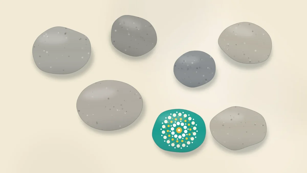 A group of bare smooth river stones in different sizes and gray-brown tones, one already painted with a bright teal and yellow dot pattern