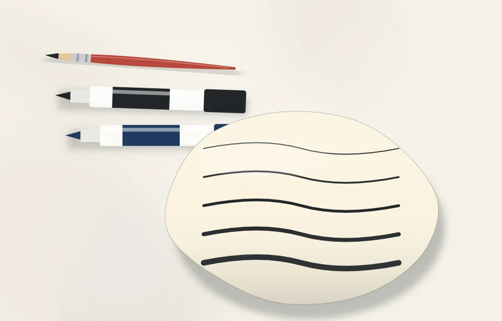 A liner brush and two paint pens above a stone showing sample lines from thin to thick