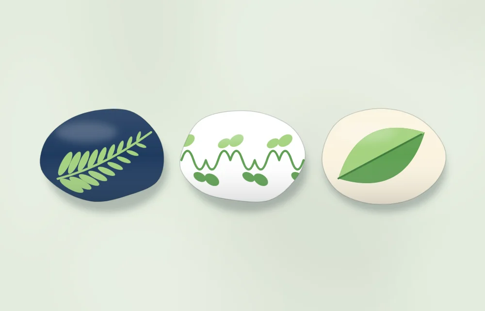 Three stones with different leaf designs: a fern frond, a curving vine with small leaves, and one leaf painted in two tones of green