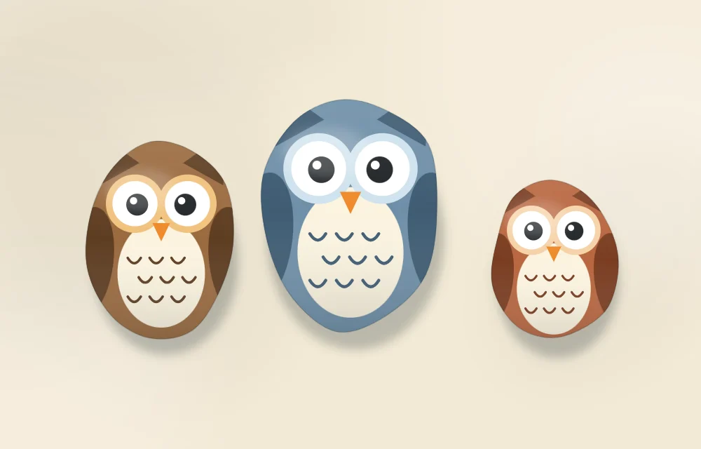 Three owl stones of different sizes and colors standing in a row